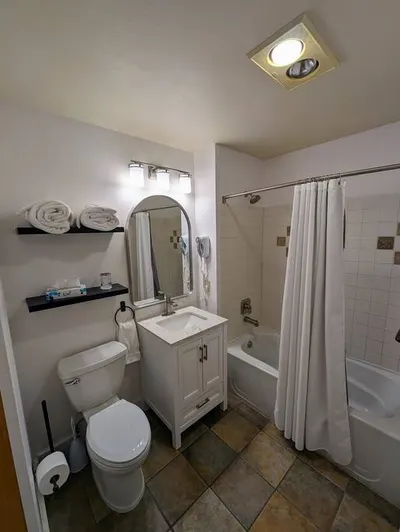 Bathroom with vanity, tub, and shelved towels
