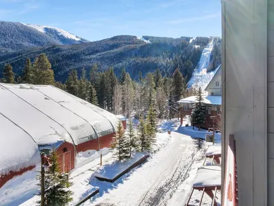 Winter view from balcony with snow-covered rooftops and ski slopes